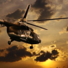 A helicopter flying in the sky at sunset.