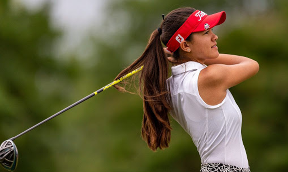 A woman in white shirt and red hat holding golf club.